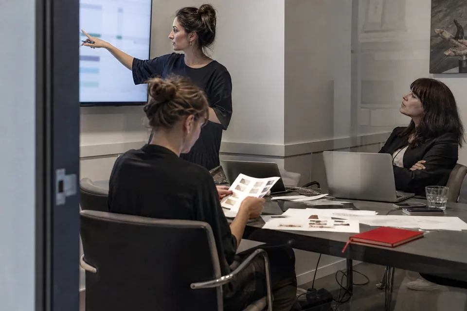 Two agency strategists presenting name options to a client in a glass meeting room