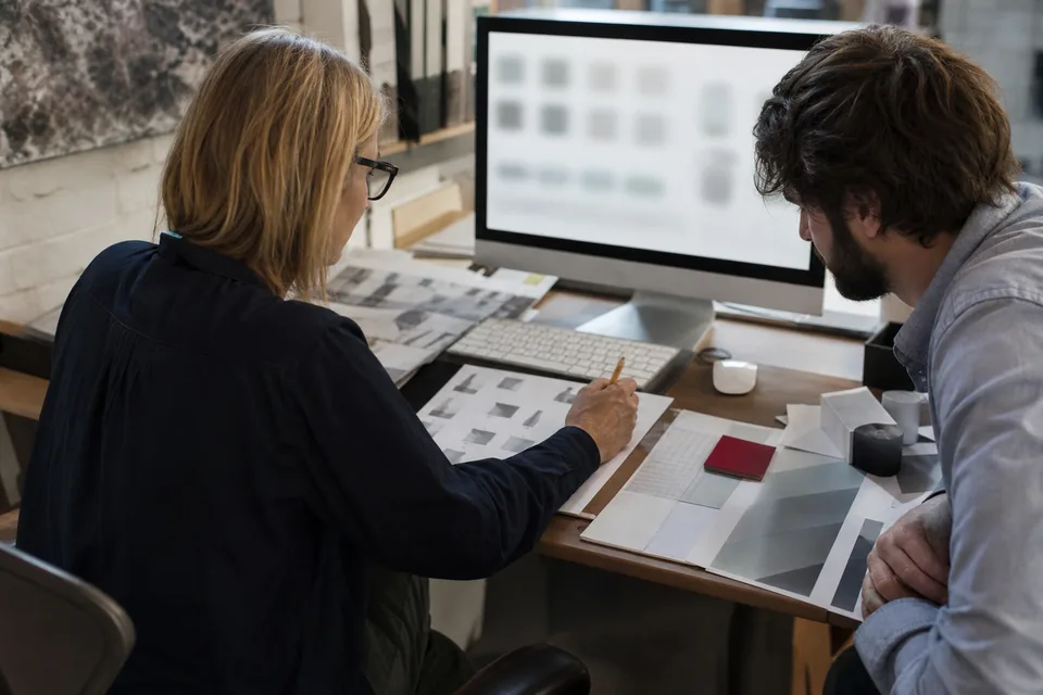 Startup head of brand and a colleague comparing a shortlist of domain names on a large monitor