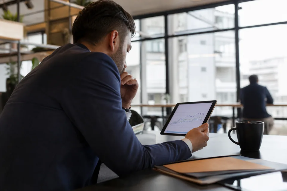 Investor in a coworking space reviewing broker fees on a tablet